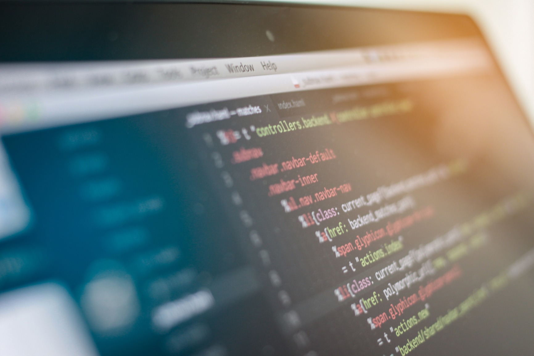 programmering-php-javascript-seo-wordpress Koding på skjerm med fokus på PHP, JavaScript og SEO. Kodevindu med fargerik tekst i ulike programmeringsspråk, svart bakgrunn og lysrefleksjoner fra skjermen.